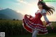 A woman in a red and white dress standing in a field.