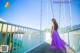 A woman in a purple dress standing on a bridge.