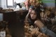 A woman sitting in front of a bunch of dried flowers.