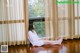 A woman sitting on the floor in front of a window.