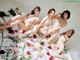 A group of naked women sitting on top of a bed of flowers.