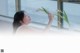 A woman holding a vase of flowers in front of a window.