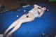A naked woman laying on a pool table.