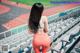 A woman in a sports bra top and leggings standing in a stadium.