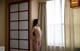 A naked woman standing in front of a window.