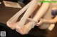 A woman tying up her bare feet on a table.